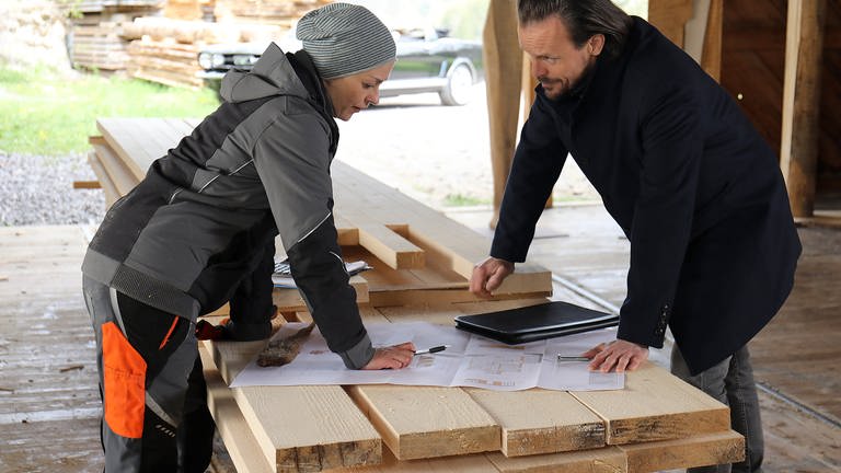 Constantin und Sophie brüten über Bauplänen, die auf einem Stapel Holz liegen (Foto: SWR, Johannes Krieg)