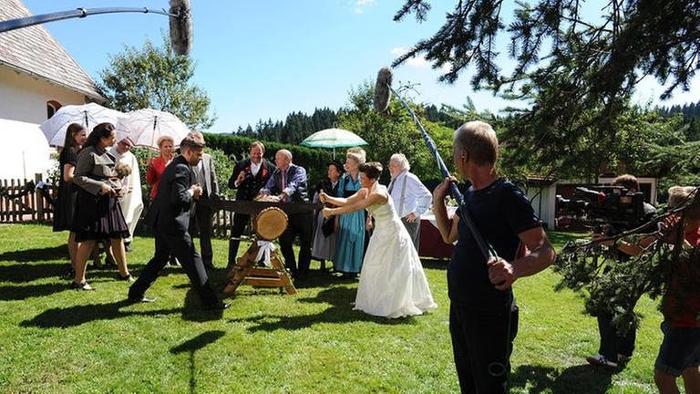 Das Brautpaar muss einen Baumstamm zersägen, die Gäste stehen drumherum und feuern sie an (Foto: SWR, SWR/Stephanie Schweigert -)