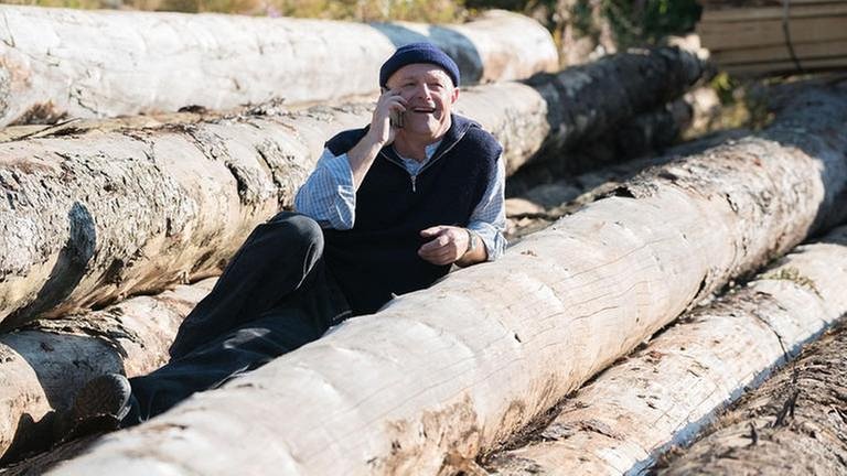 Tony liegt auf Holzstämmen und telefoniert (Foto: SWR, SWR/Stephanie Schweigert -)