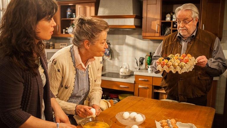 Johanna und Eva stehen am Tisch, vor sich ausgeblasene Eier, Hermann hält ein Tablett mit bemalten Ostereiern (Foto: SWR, SWR/Jasmin Vollmer -)