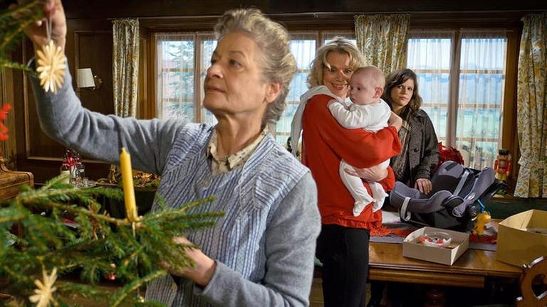 Johanna schmückt den Weihnachtsbaum, im Hintergrund hält Kati ihre Enkelin Carlotta, Eva guckt skeptisch (Foto: SWR, SWR/Peter Sebera -)
