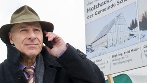 Franz Faller steht vor der Baustelle seines Heizkraftwerkes und telefoniert (Foto: SWR, SWR/Stephanie Schweigert -)