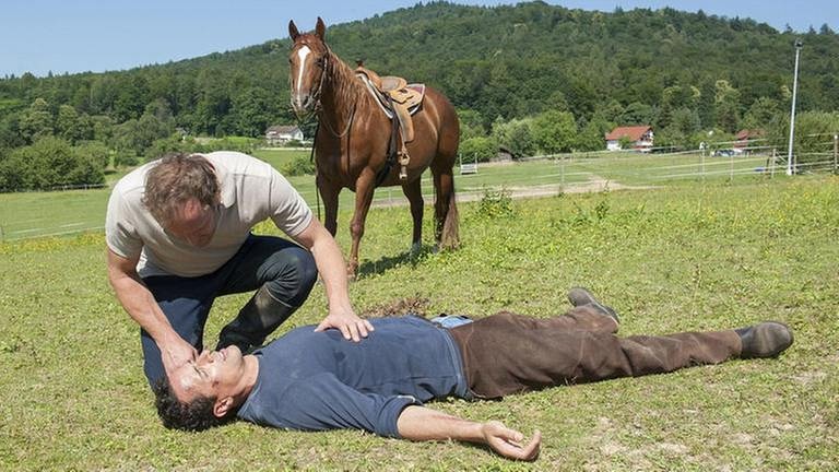 Bernd beugt sich über Matthias, der vom Pferd gefallen ist und am Boden liegt (Foto: SWR, SWR/Stephanie Schweigert -)