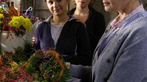 Jenny und Bea sehen zu, wie Johanna im Brunnengang Blumen bindet (Foto: SWR, SWR -)