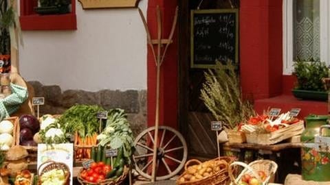 Außenansicht des Hofladens, Marktstand mit Obst und Gemüse.