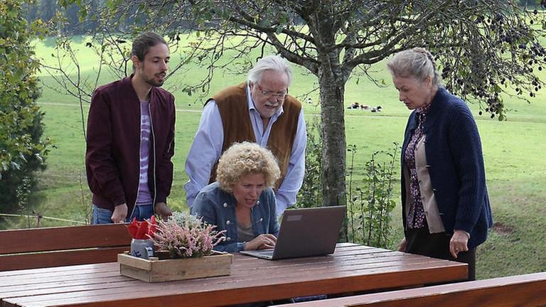 Albert, Hermann und Johanna stehen bei Bea, die draußen vor ihrem Laptop sitzt (Foto: SWR, SWR/Johannes Krieg -)