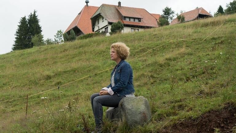 Bea sitzt unterhalb des Fallerhofes auf einem großen Stein (Foto: SWR, SWR/Stephanie Schweigert -)