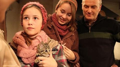 Annika hat ein kleines getigertes Kätzchen im Arm, Lena und Karl stehen hinter ihr und schauen auf das Kätzchen (Foto: SWR, SWR/Ralf Nowack -)