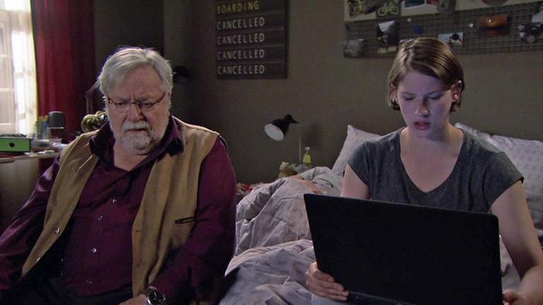 Hermann sitzt neben Celine auf dem Bett, Celine hat einen Laptop auf dem Schoß und recherchiert für Hermann (Foto: SWR, SWR -)