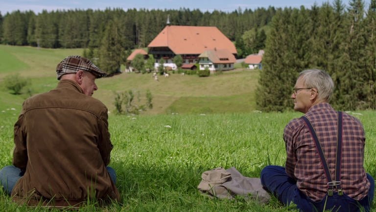 Heinz und Karl sitzen auf der Wiese mit Blick auf den Fallerhof (Foto: SWR)