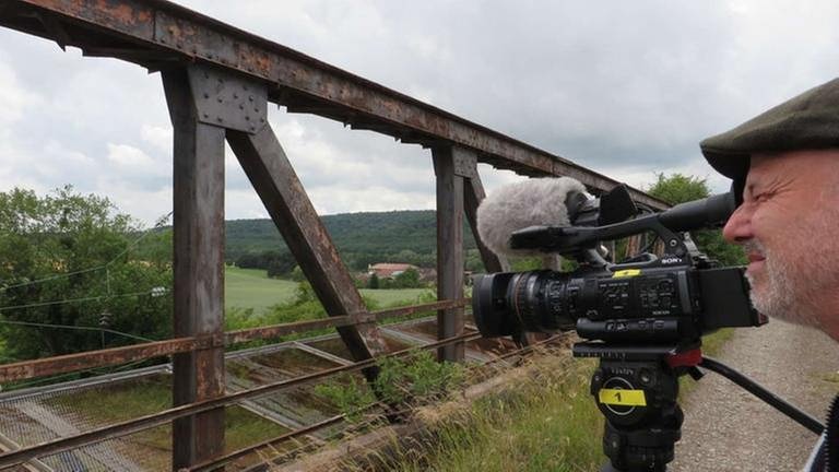 Filmautor Bernhard Foos wartet auf einer verrosteten Stahlbrücke auf den Museumsbahnzug der A.M.E.L.F. (Foto: SWR, SWR - Bernhard Foos)