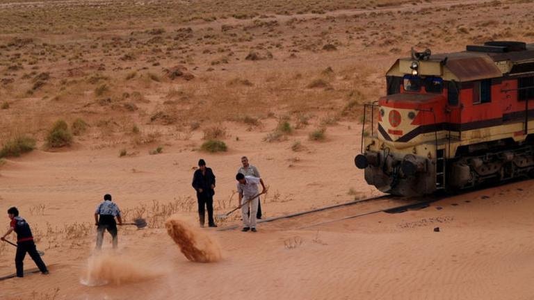 Sandverwehungen auf dem Gleis. Fleißige Helfer schaufeln dem Zug den Weg frei. - Die Sahara  bedeckt 9 Millionen  Quadratkilometer, knapp 20 % sind reine Sandwüste. (Foto: SWR, SWR - Andreas Stirl)