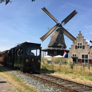 Das schönste Motiv auf der 20 km langen Museumsbahnstrecke Hoorn – Medemblik: die Kornmühle „De Herder“ auf dem Deich vor Medemblik. Samstags bewegt sie ihre Flügel und macht Mehl.