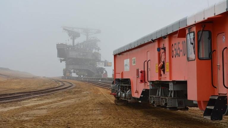 Die orange Gleisrückmaschine bereitet die Schienenanlage für den Abraumbagger im Hintergrund vor. Auch er bewegt sich auf Gleisen. (Foto: SWR, Grit Merten)
