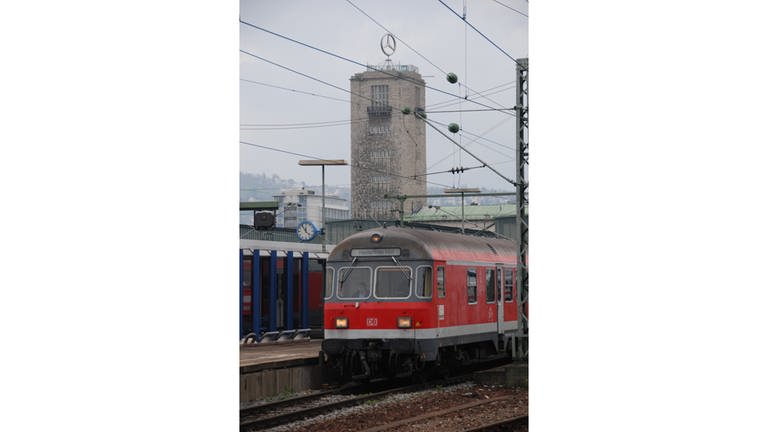 Roter Zug steht im Bahnhof. Im Hintergrund sieht man das Mercedes-Benz-Logo