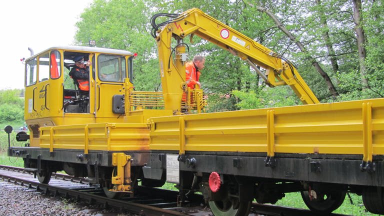Ein vielseitiges Gerät zur Instandhaltung der Wieslauterbahn ist der SKL (Schwerkraft-Kleinwagen), ein Werkstattwagen mit Anhänger Bagger in knallgelber Farbe (Foto: SWR, SWR)