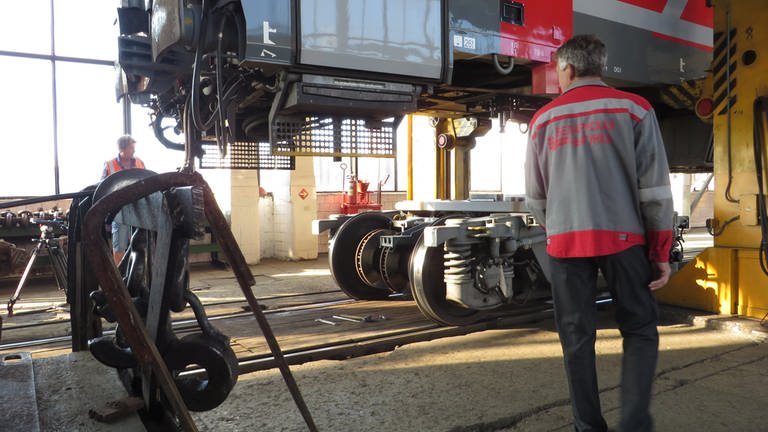 Ein Zug hängt in der Wagenhalle der weißrussischen Grenzstadt Brest, ein Kameramann steht daneben (Foto: SWR, Bernhard Foos)