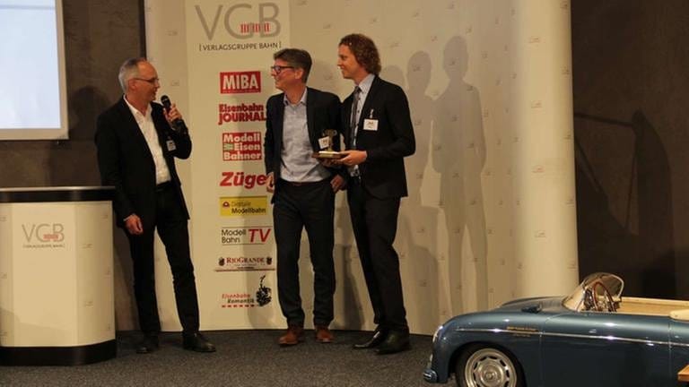 MEB Redakteur Andreas Bauer-Portner überreicht den Preis an Florian Sieber u. Uwe Müller Fa. Märklin für das TT Minitrix Modell eines offenen Schüttgutwagens (Foto: SWR, SWR - Wolfgang Drichelt)