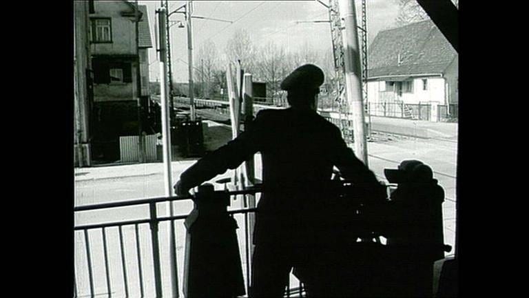 Noch werden Bahnübergänge per Hand gesperrt. (Film von 1964)