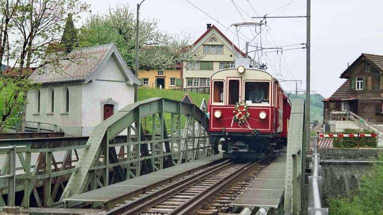 Zug Sonderfahrt fährt über eine Stahlbrücke, daneben eine kleine Kapelle