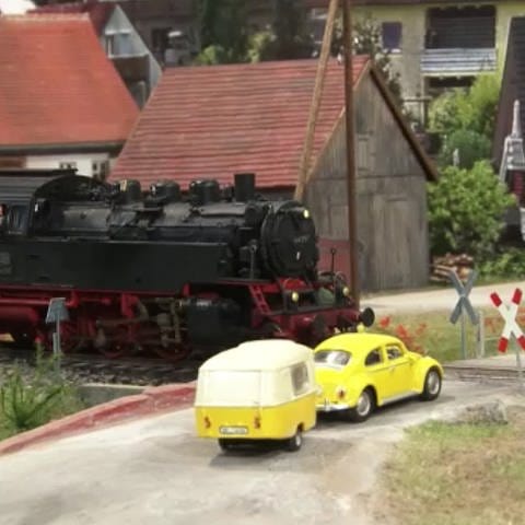 Eisenbahn und VW Käfer mit Anhänger in Miniaturausgabe