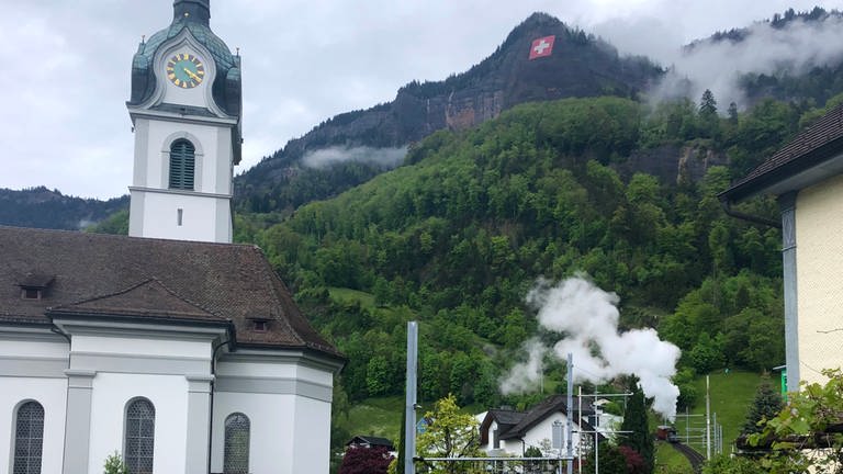 Wolken über Vitznau: unten im Bild verursacht durch die Dampflok Nr. 7 - und oben wartet der Regen an diesem Jubiläumstag.  (Foto: SWR, Kirsten Ruppel)