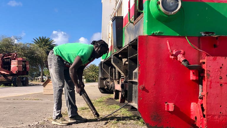 St. Clair ist einer der drei Lokführer der St. Kitts Scenic Railway. Vor der ersten Fahrt am Tag checkt er sein Fahrzeug gründlich durch.  (Foto: SWR, Kirsten Ruppel)