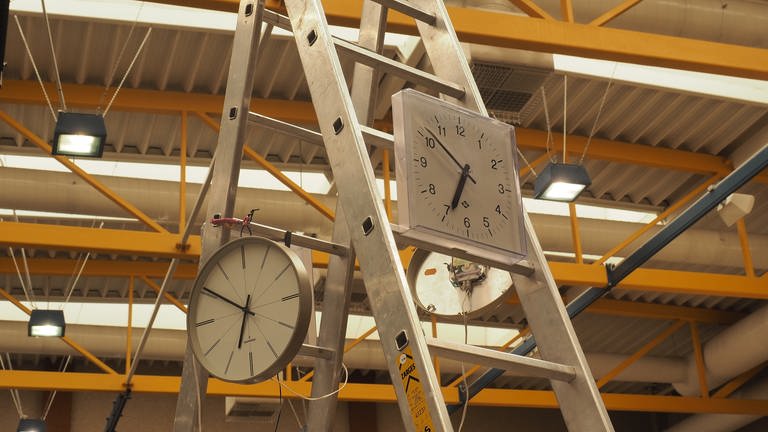 In der Halle hängen Uhren, die etwa vier Mal so schnell wie die Echtzeit laufen. 