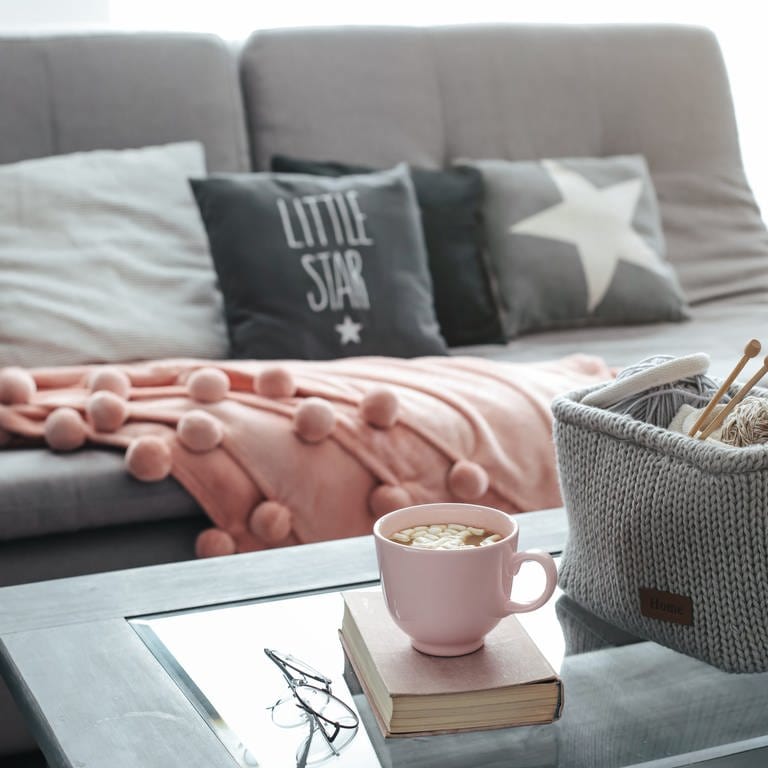Couch mit Kissen und Häkelkorb mit Wolle auf dem Tisch (Foto: Colourbox)