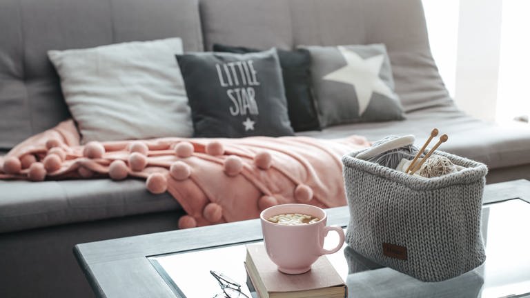 Couch mit Kissen und Häkelkorb mit Wolle auf dem Tisch (Foto: Colourbox)