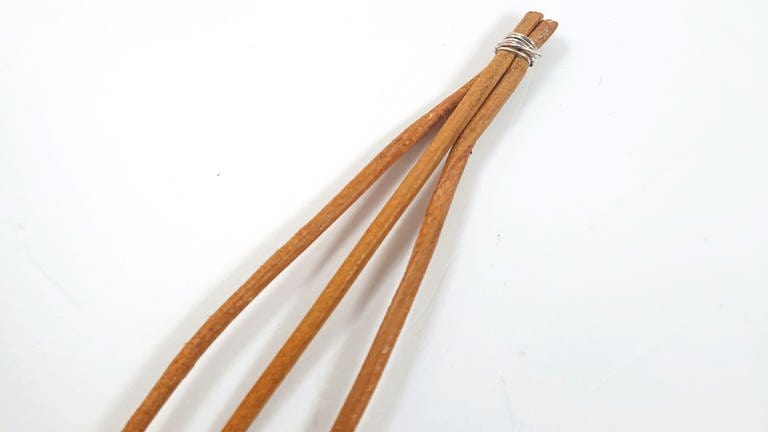 Das Lederband dreimal auf 60-80 cm Länge zuschneiden und die Stränge oben fest mit einem dünnen Schmuckdraht zusammen binden. (Foto: Lisa Vöhringer)