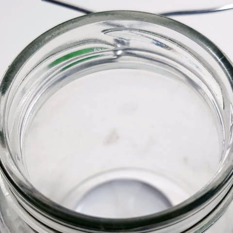 Etwas Draht abschneiden und diesen um den Rand des Marmeladenglases legen. Rechts und links vom Glas den Draht zu runden Ösen biegen und die Drahtenden anschließend fest verdrehen.  (Foto: Lisa Vöhringer)