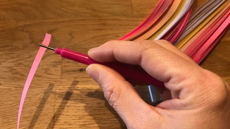 Die Quillingpapier-Streifen vorne in den Schlitz des Quilling-Stiftes einführen. (Foto: Karolin Happel)