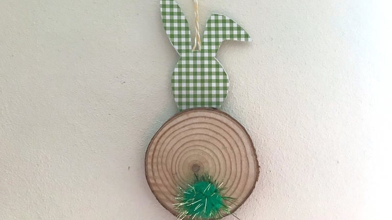 Auf der Holzscheibe unten mittig einen Pompom, ein Plüschbällchen, einen farbigen Knopf als Schwänzchen festkleben.  (Foto: Karolin Happel)