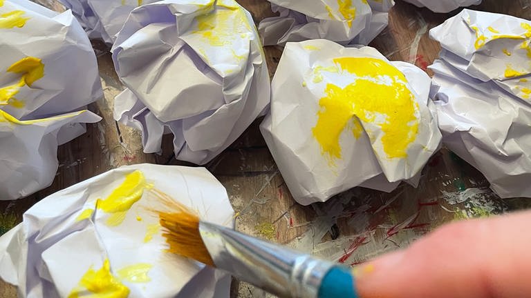 Weißes Papier zusammen knüllen. Die fertigen Papierkugeln stellenweise etwas mit gelber Farbe bemalen.  (Foto: Karolin Happel)