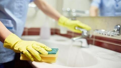 Mit einem Schwamm wird ein Badezimmer Waschbecken gereinigt. (Foto: Getty Images, Thinkstock -)