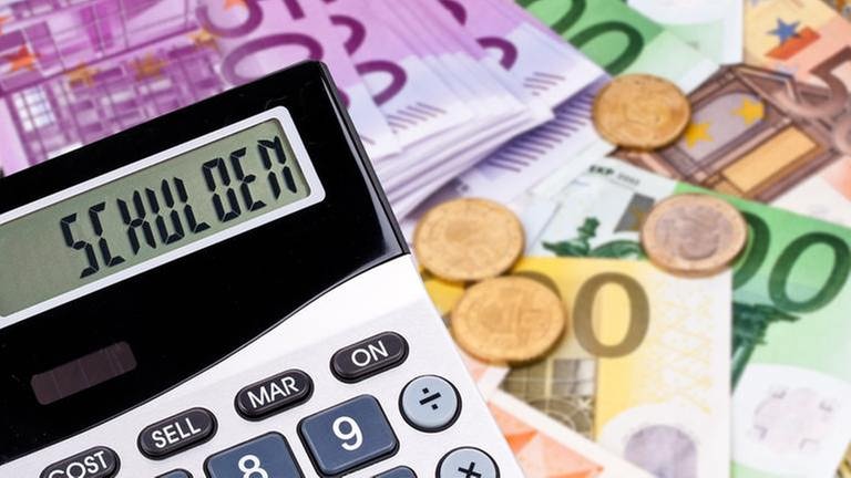 Schulden auf einem Taschenrechner im Hintergrund Euroscheine