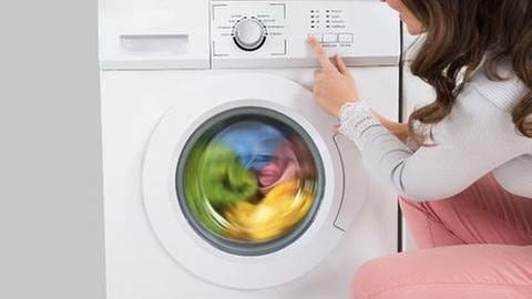 Eine Frau neben einer Waschmaschine. (Foto: Getty Images, Thinkstock -)