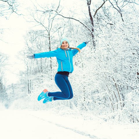 Frau springt in Schneelandschaft in die Luft (Foto: Colourbox)