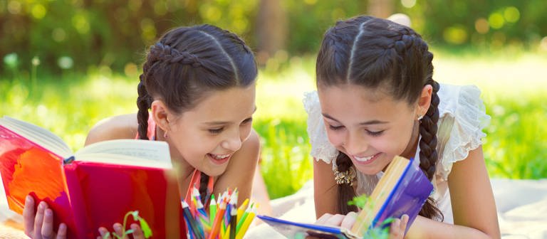 Mädchen lesen auf der Wiese (Foto: Colourbox)