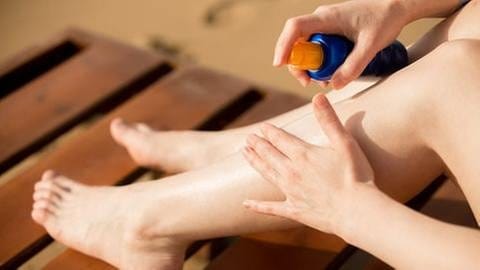 Eine Frau reibt sich die Beine mit Sonnencreme ein (Foto: Getty Images, Thinkstock -)