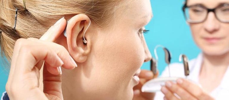Frau kriegt ein passendes Hörgerät von einer Ärztin (Foto: Getty Images, Thinkstock -)