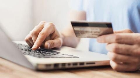 Mann bestellt mit seiner Kreditkarte und seinem Laptop etwas im Internet. (Foto: Getty Images, Thinkstock - Poike)