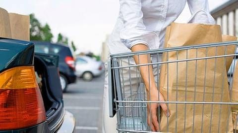 Eine Frau belädt auf einem Supermarkt-Parkplatz ihr Auto mit Einkäufen (Symbolbild). (Foto: Getty Images, Thinkstock -)