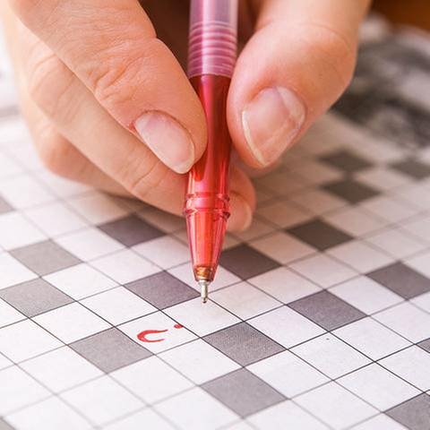 Eine Frauenhand hält einen Stift in der Hand. Sie liegt auf einem noch ungelöstem Kreuzworträtsel mit nur einem eingetragenen  Fragezeichen. (Foto: Colourbox, Foto: Colourbox.de -)