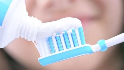 Eine Frau gibt Zahnpasta auf eine Zahnbürste. (Foto: Getty Images, Thinkstock -)