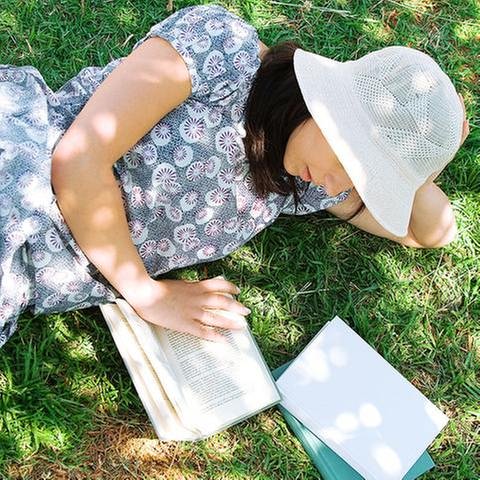 Junge Frau liegt im Schatten unter einem Baum und liest ein Buch. (Foto: Colourbox, Model Foto: Colourbox.de -)