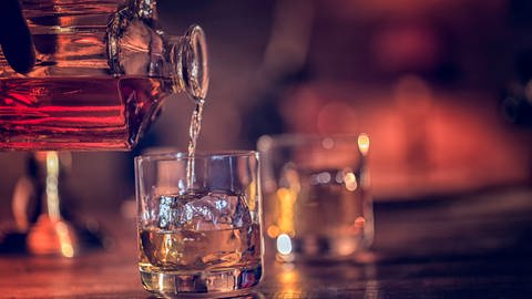 Whiskey fließt aus Flasche ins Glas (Foto: Getty Images, GMVozd)