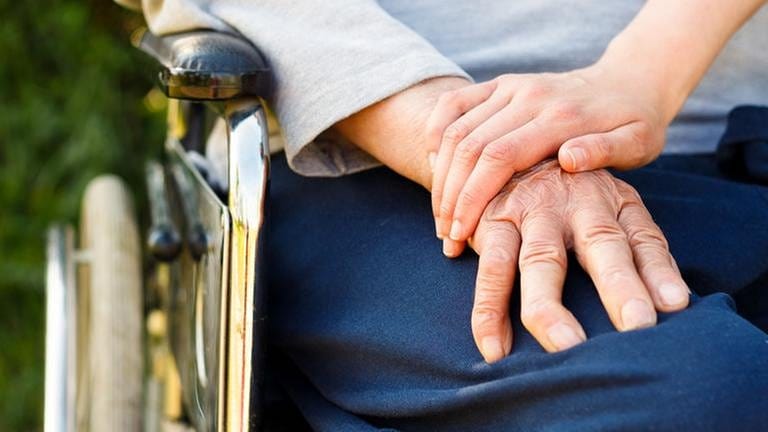 Eine junge Hand hält die Hand einer älteren Person im Rollstuhl. (Foto: Colourbox, Foto: Colourbox.de -)