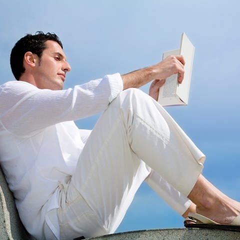 Mann in weißer Leinen-Kleidung liest ein Buch (Foto: istock photo)